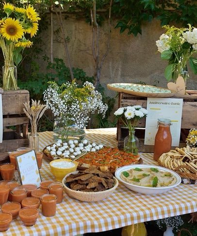 Buffet salé dressé en extérieur : gaspacho, houmous, bruschettas et pains grillés